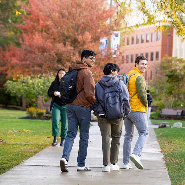 Three CWRU students walking through the quad surrounded by fall foliage.