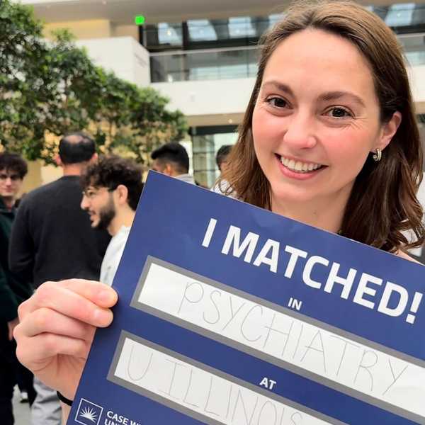 A CWRU School of Medicine student smiling and holding a sign that reads “I Matched.” 