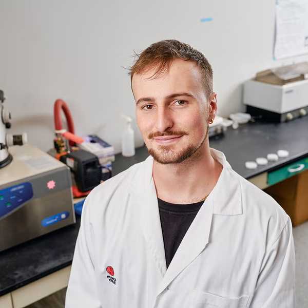 CWRU alumnus Franco Kraiselburd posing for a headshot in a lab, wearing a white lab coat.