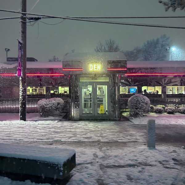 Snow falling around The Den on CWRU’s campus, with the building’s neon lights as the focal point.